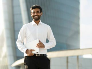 smiling-handsome-businessman-holding-laptop-comput-2023-11-27-05-13-12-utc-1