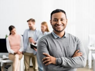 smiling-indian-businessman-with-crossed-arms-stand-2023-11-27-05-36-32-utc-1