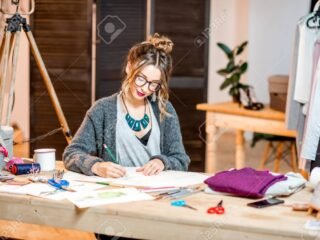92337128-young-female-fashion-designer-sketching-drawings-of-the-clothes-sitting-at-the-beautiful-office-with