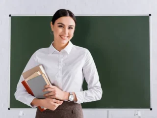 stock-photo-teacher-books-smiling-camera-classroom